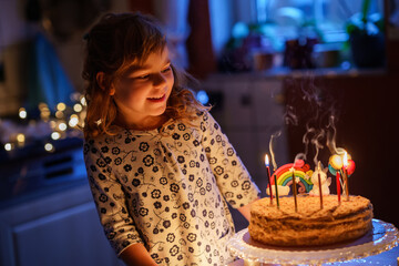 Happy little preschool girl celebrating birthday. Cute smiling child with homemade princess cake, indoor. Happy healthy toddler blowing six candles on cake