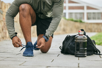Fitness, sports shoes and black man tie before outdoor cardio exercise or workout in the park. Sport, runner and African male athlete preparing for endurance training for race, challenge or marathon.