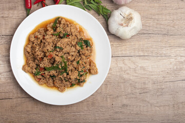 Pad kaprao, minced chicken in white plate on wooden background