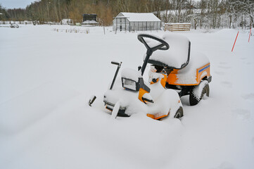 yellow riding lawn mower covered in snow