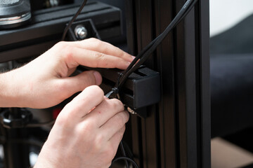 worker using black plastic clamp tie to tight cables