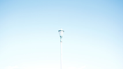 Long, white streetlights against the blue sky