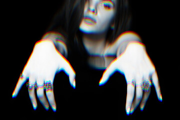 Portrait of beautiful woman with many various rings on her fingers holding her hands on dark glass surface. Selective focus. RGB color split effect applied. Futuristic looking style