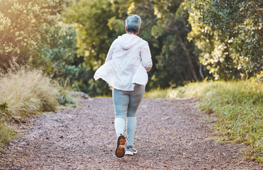 Fototapeta premium Fitness, back and senior woman running in nature, park or outdoors alone. Sports, marathon and retired elderly female training, exercise jog or cardio workout for cardiovascular health and wellness.