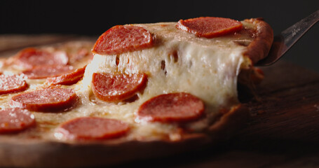 Close up shot of taking a piece of freshly baked pizza with tasty stretchy cheese. Delicious...