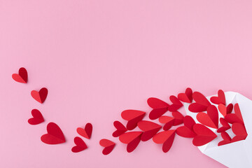 Creative composition on Saint Valentine day. Envelope and paper red hearts for love message on pink...
