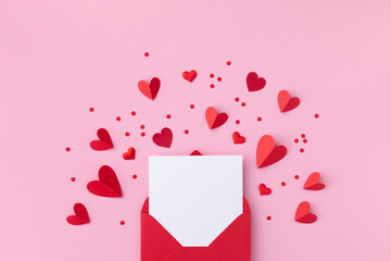 Fototapeta premium Saint Valentine day holiday background with envelope, paper card and various red hearts for love romantic message. Flat lay composition..