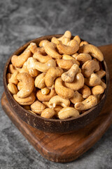 Cashew nuts on dark background. Fresh cashews in coconut bowl. Studio shoot. close up