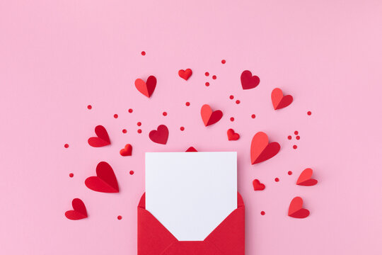 Saint Valentine day holiday background with envelope, paper card and various red hearts for love romantic message. Flat lay composition..