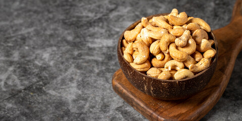 Cashew nuts on dark background. Fresh cashews in coconut bowl. Studio shoot. Copy space. Empty space for text
