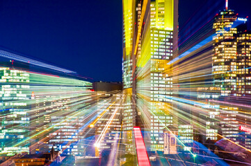 Fototapeta na wymiar Die künstlich beleuchteten Hochäuser der Skyline von Frankfurt am Main am Abend aufgenommen mit Zoomeffekt
