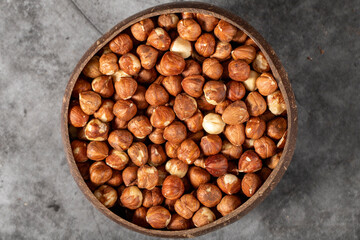 Fresh hazelnut nuts on dark background. Nuts in a coconut bowl. Studio shoot. Top view