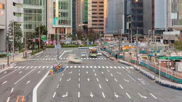 Light traffic and pedestrians on wide road between office buildings and Japan Railways station