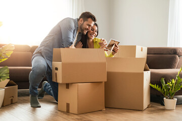 Smiling couple unpacking boxes in new home