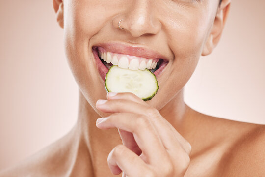 Hand, Mouth And Cucumber With A Model Black Woman Biting A Vegetable In Studio On A Beige Background. Health, Beauty And Skincare With A Young Female Eating A Slice Of Veg For Natural Wellness