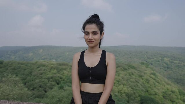 India active sport woman sitting with confidence after exercise outdoors. Portrait of beautiful Asian girl in sportswear smile, look at camera after running workout in morning.