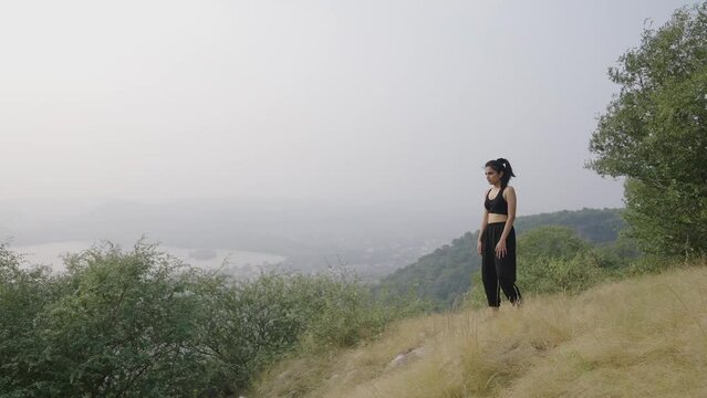 young Asian girl smiling climb hulking and standing tiredness with beautiful morning view on the top of mountain.Indian beautiful women climb at the top of mountain in the morning.