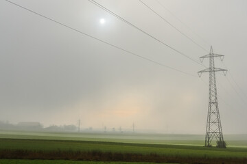 single power pole with dense fog and sun at the sky