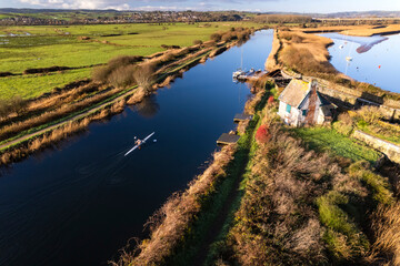 Aerial shot of person rowing along Exeter Ship canal and Topsham Lock in early morning light