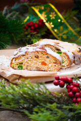 Christmas stollen its a Traditional Dresdner German Christmas cake Stollen with raising, berries and nuts. Sliced stollen on paper and Christmas decoration. Selective focus, shallow depth of field