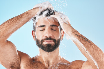 Hair care, face water splash and shower of man in studio isolated on a blue background. Water...
