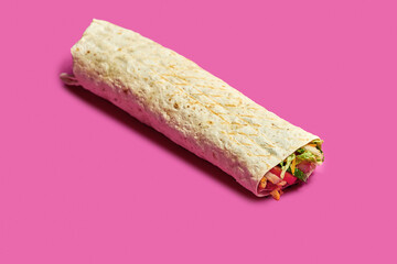 Large shawarma with chicken, vegetables and sauce on a pink background.