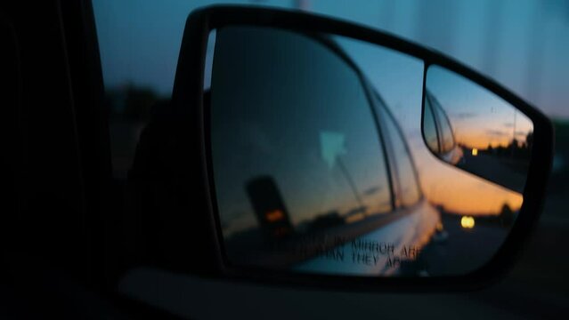 Object in the mirror are closer than it appear. Reflection of the sunset in the rearview mirror of a car. Travel by car. Car rear view mirrors