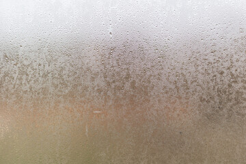 Closeup shot of a steamy window with water drops made in dull day.