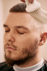 Obraz premium Barber shaving bearded man in barber shop