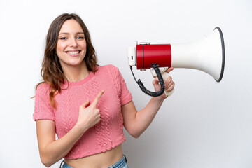 Young caucasian woman isolated on white background holding a megaphone and pointing side