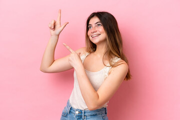 Young caucasian woman isolated on pink background pointing with the index finger a great idea