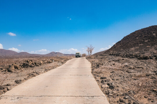 A tourist safari van in the desert landscapes of Lake Turkana in Loiyangalani District, Kenya