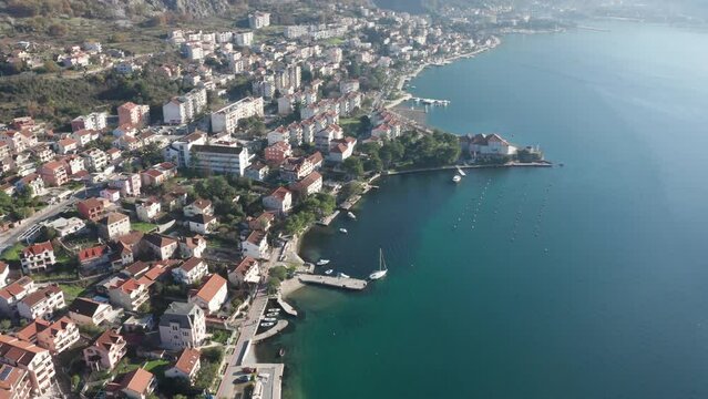 Kotor Montenegro waterfront - Roofs on houses and buildings along the coastline, in residential neighborhood of Dobrota, between rocky hills and Mediterranean sea bay. Aerial drone view.