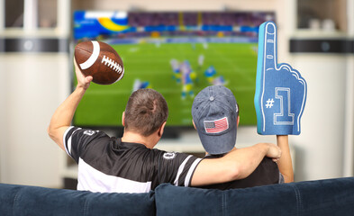Fans of american football. Father and son watching TV.