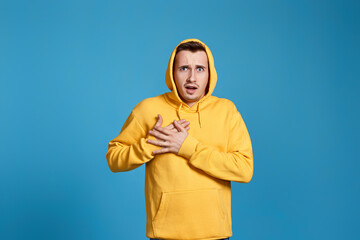 young man in yellow sweatshirt with hands on chest