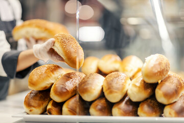 Close up of bakery department worker arranging rolls.