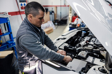 An auto mechanic repairing car under the hood at the mechanic's shop.