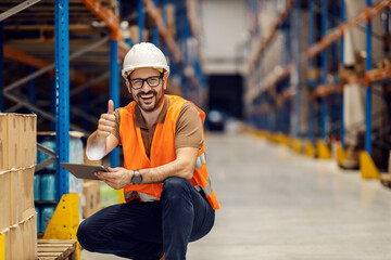 A distribution center worker is inventorying on tablet and giving thumbs up while smiling at the camera.