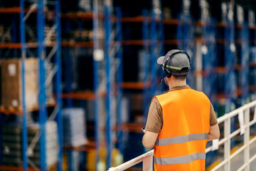 Rear view of storage manager controlling logistics from height.