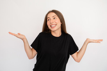 Portrait of careless young woman shrugging shoulders and smiling over white background. Caucasian...