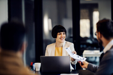 A businesswoman is taking paperwork and checking on it during business meeting.