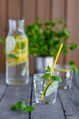 Glass of water with lime and mint on a old wooden table