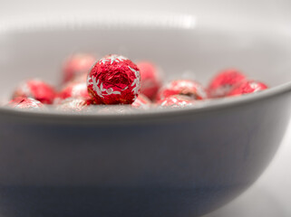 close-up of several red foil wrapped christmas chocolate ball sweets in a blue bowl