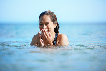Young woman swimming in ocean, happy on beach vacation and freedom of summer adventure in...