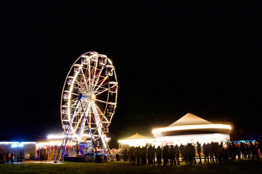 One Ferris wheel and 3 enigmatic rides running at full speed in the dark, at a funfair in Bokrijk in Limburg, Belgium.