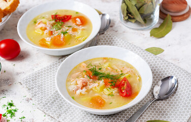 Fish soup with salmon, vegetables and rice in white bowl.