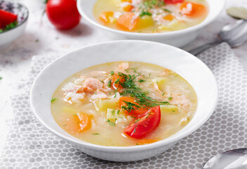 Fish soup with salmon, vegetables and rice in white bowl.