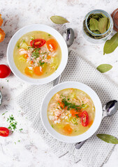 Fish soup with salmon, vegetables and rice in white bowl. Top view, above