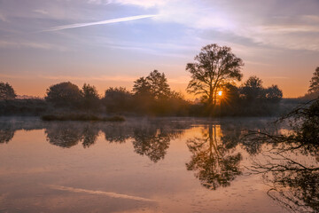 Wschód słońca. Jesienny poranek nad dziką rzeką w Polsce. Odbicia w wodzie. Wodny krajobraz....