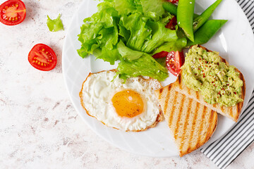 Fried egg, fresh salad and avocado guacamole sandwiches. Top view, concept of a healthy lifestyle